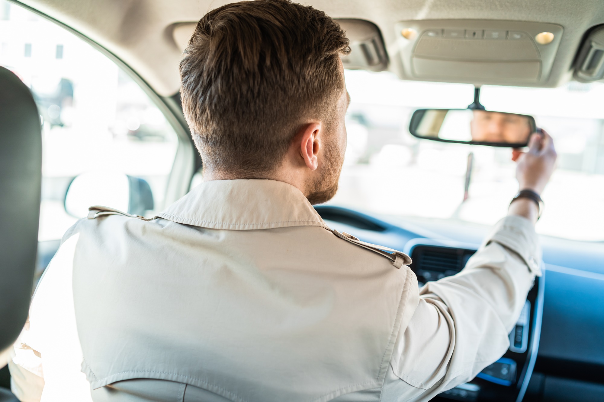 Mężczyzna patrzący w lusterko wsteczne w samochodzie, podczas jego ustawiania i regulowania