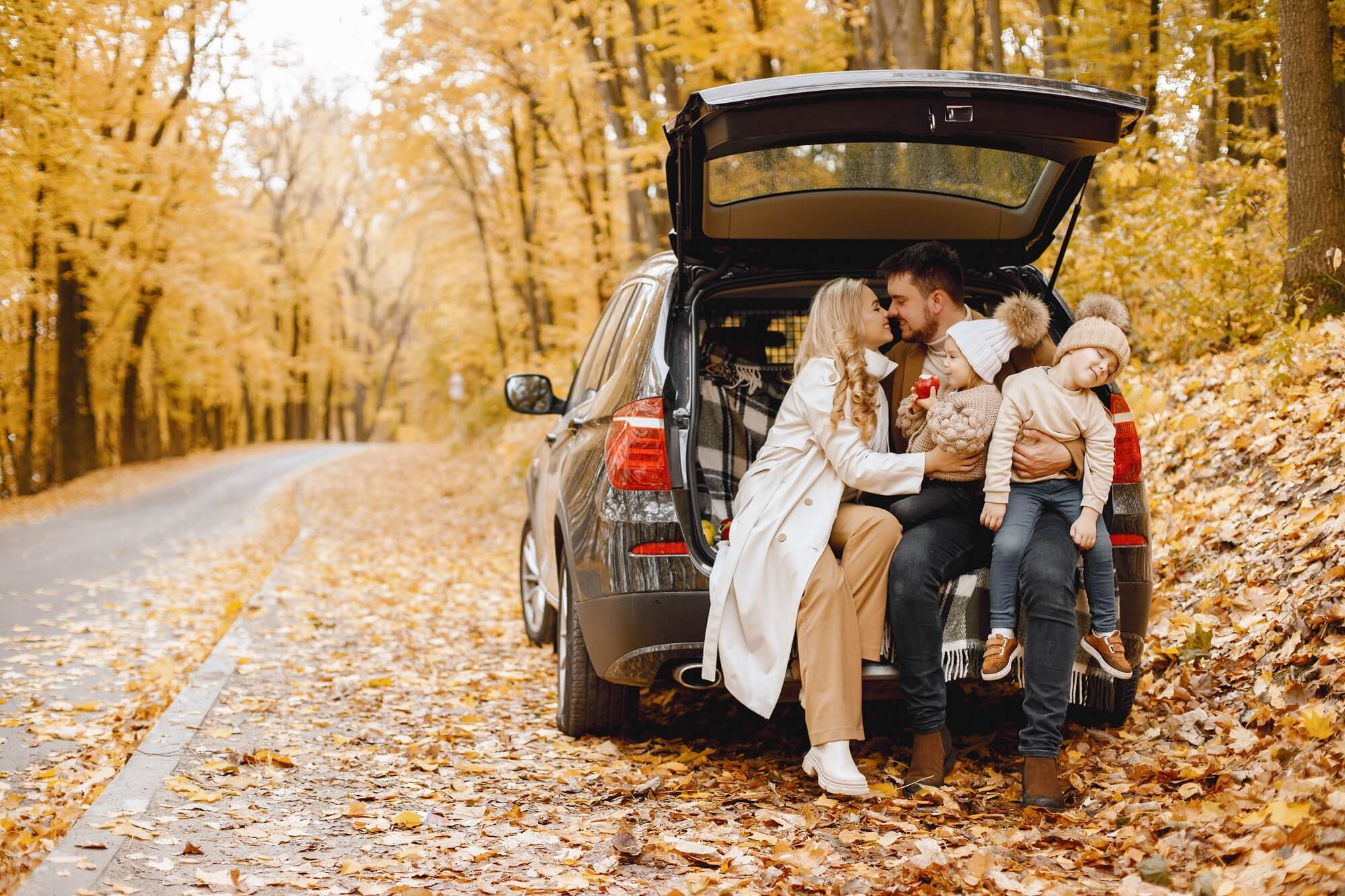 rodzina z dwójką dzieci w aucie hatchback na tle jesiennego lasu