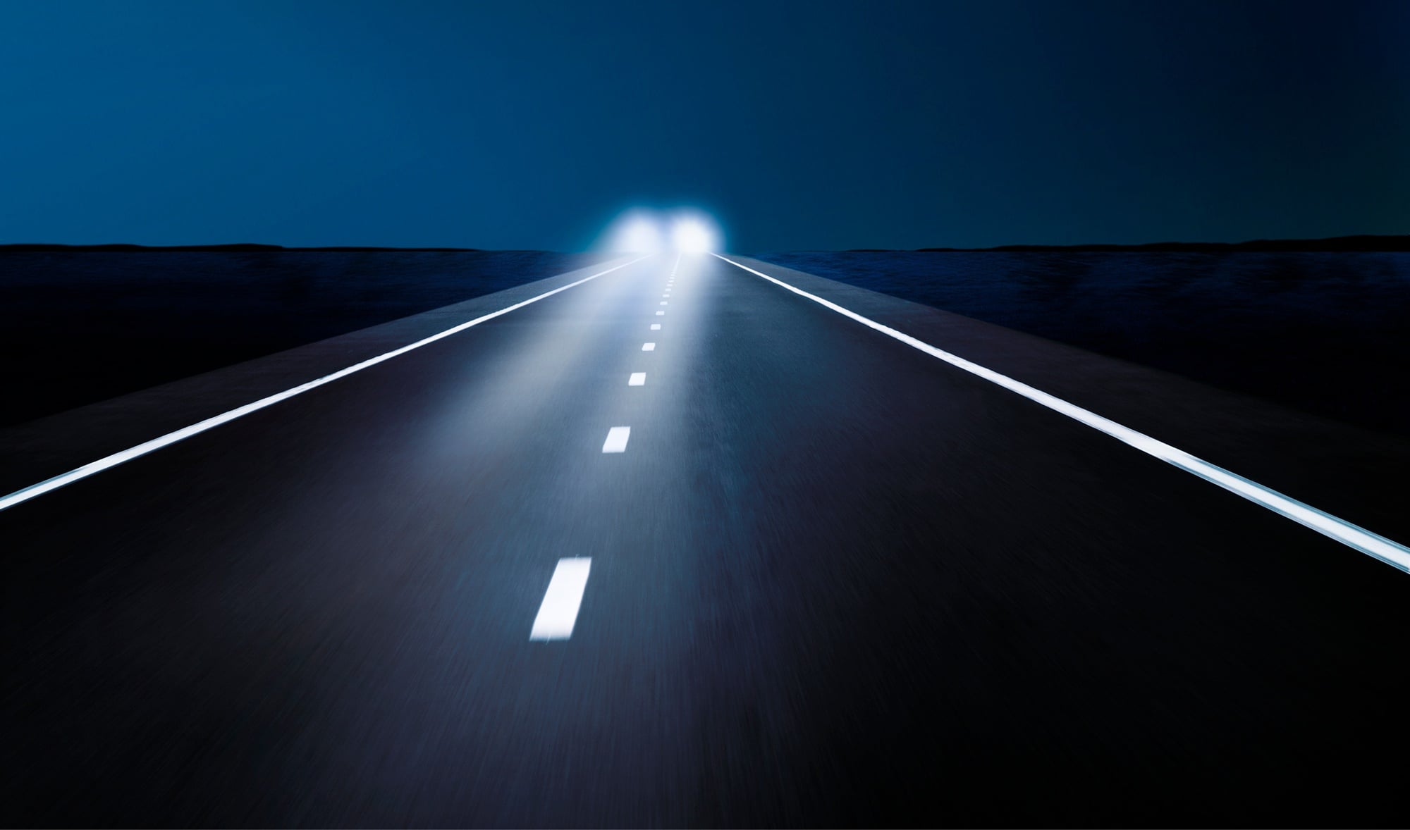 Stojące na drodze auto z zapalonymi światłami długimi